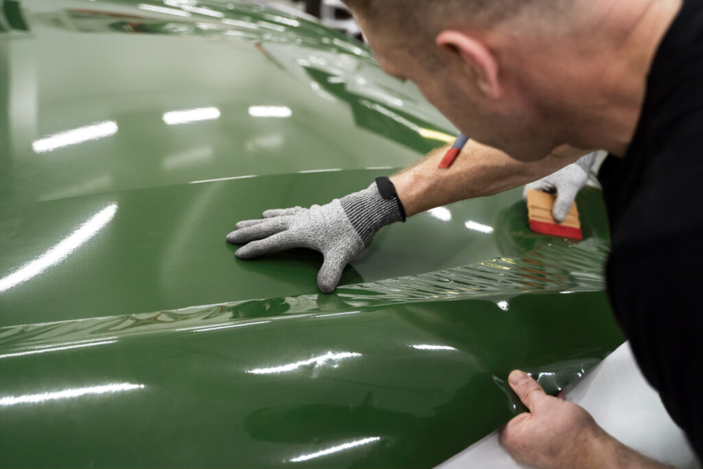 Technician performing paint matching and sensor calibration on a luxury vehicle
